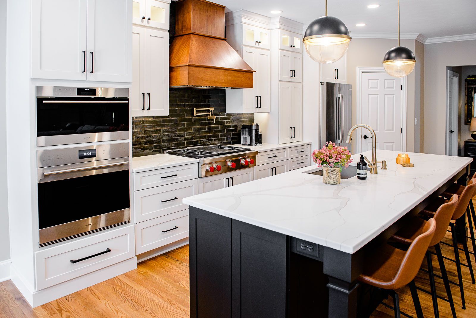 A kitchen with white cabinets , stainless steel appliances , and a large island.