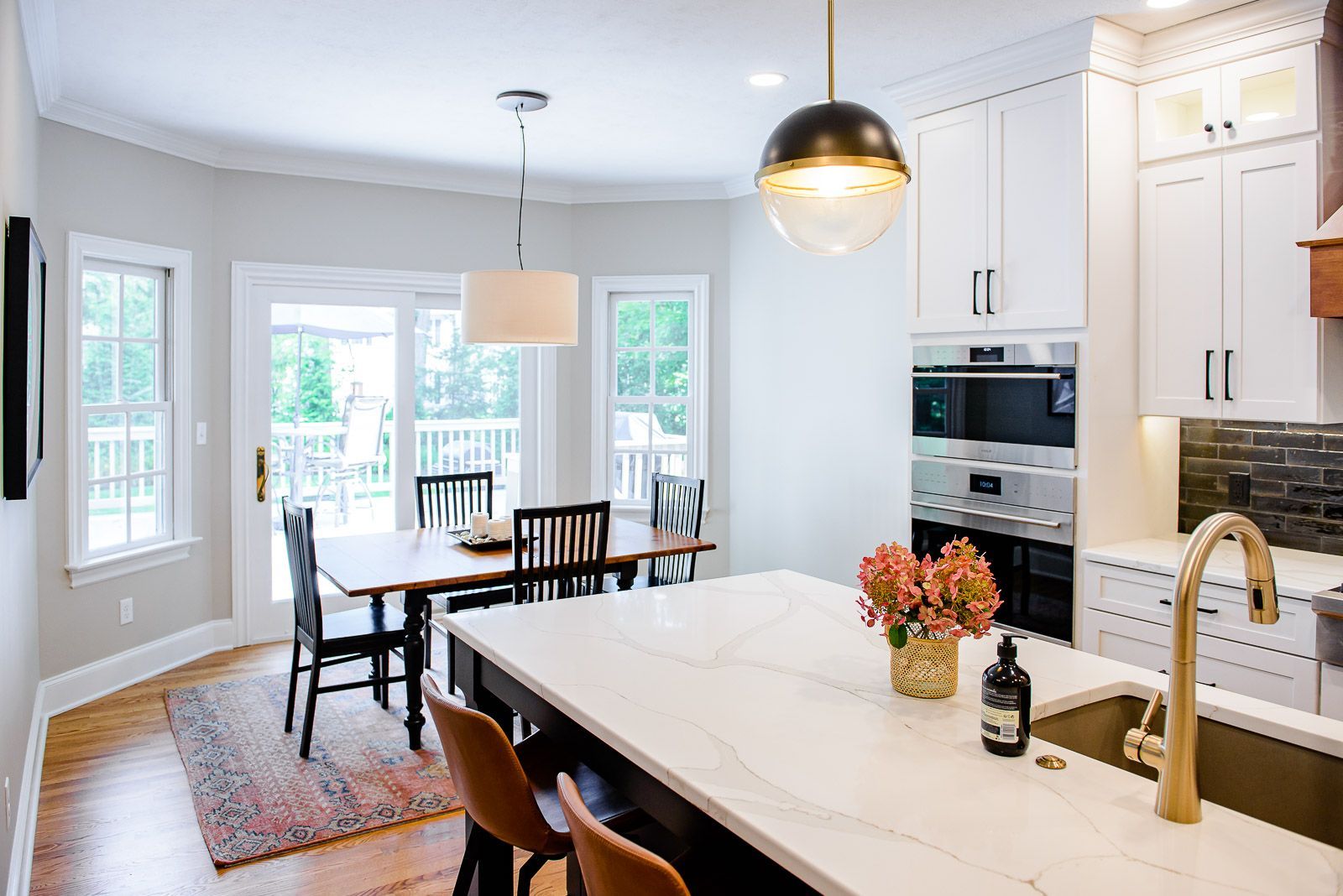 A kitchen with a large island , sink , table and chairs.