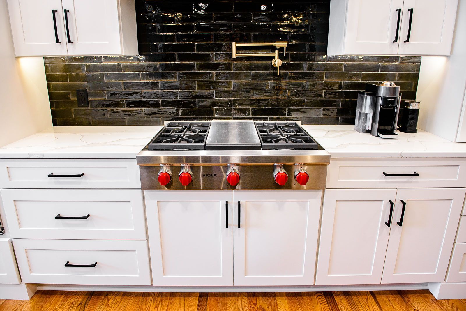 A kitchen with white cabinets and a stove top oven.