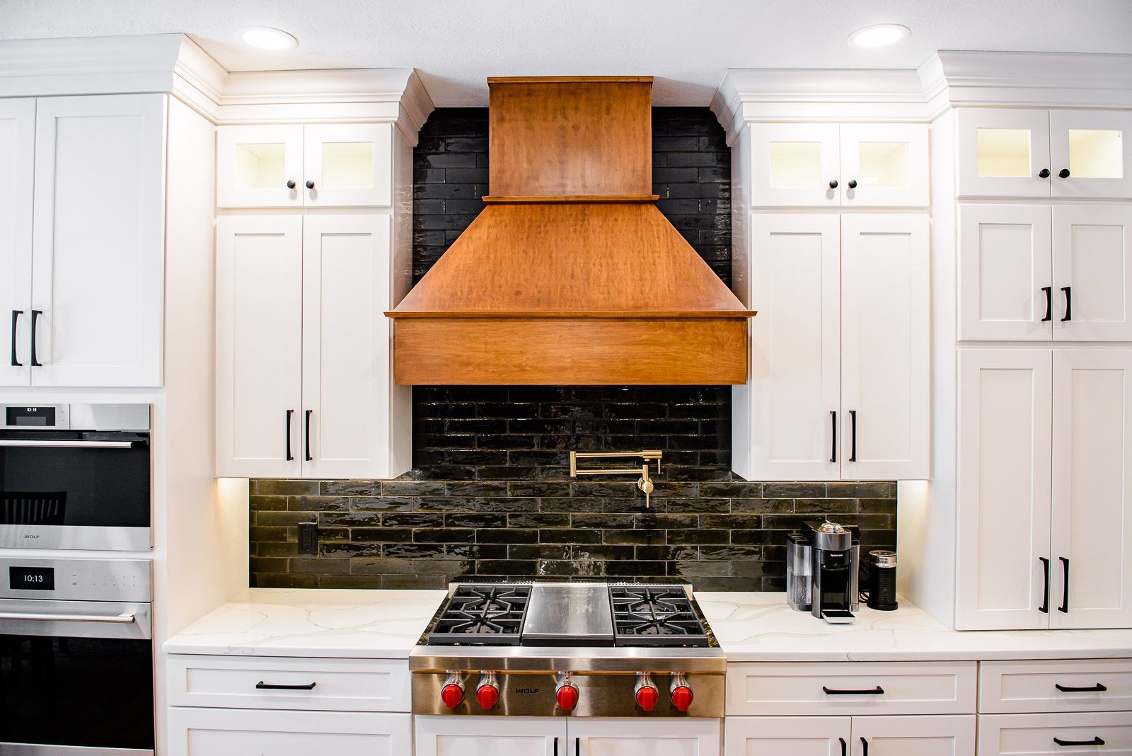 A kitchen with white cabinets and a copper hood above the stove.