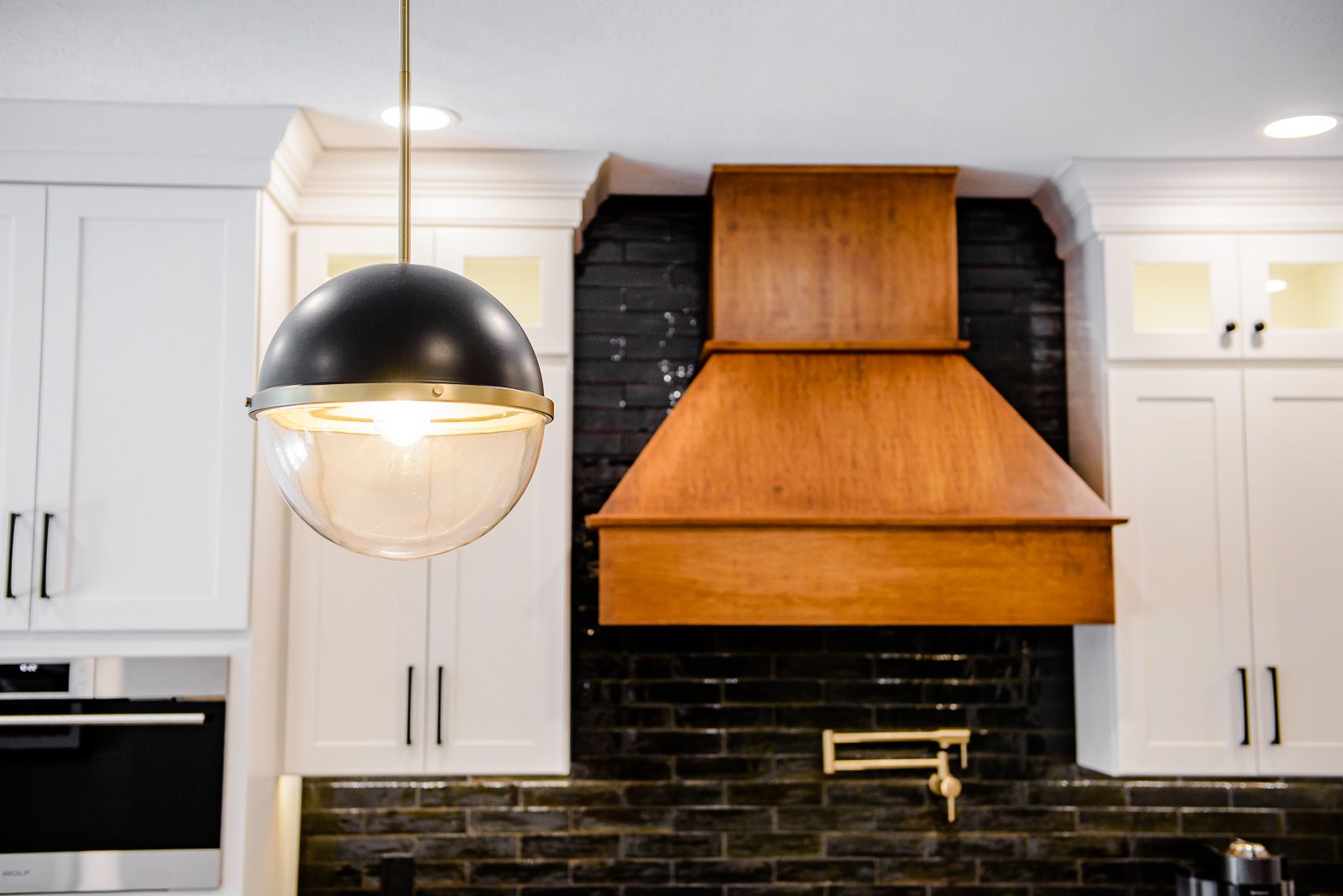 A kitchen with white cabinets and a wooden hood above the stove.