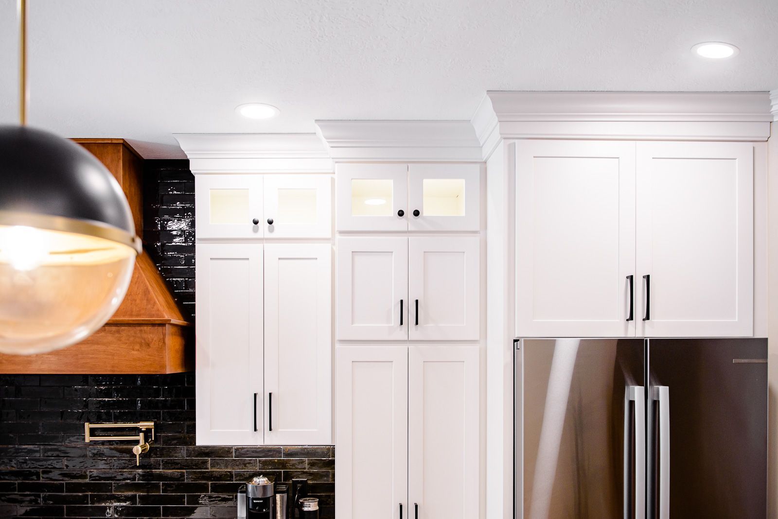 A kitchen with white cabinets and a stainless steel refrigerator.
