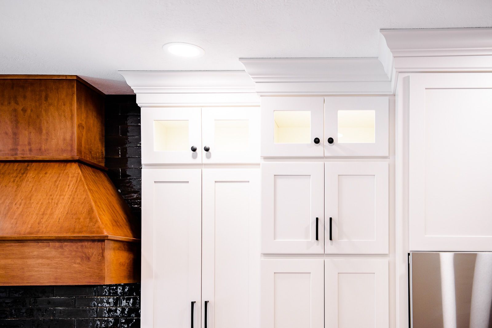 A kitchen with white cabinets and a wooden hood.