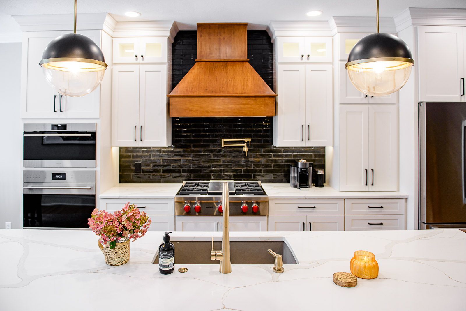 A kitchen with white cabinets , stainless steel appliances , a sink and a stove.