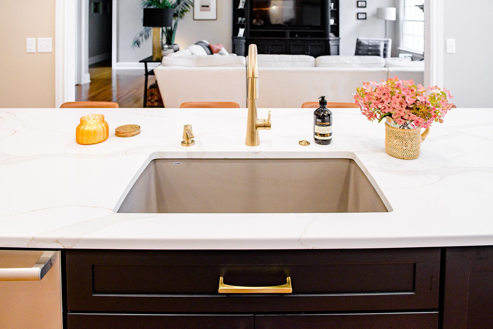 A kitchen sink with a faucet and a vase of flowers on the counter.