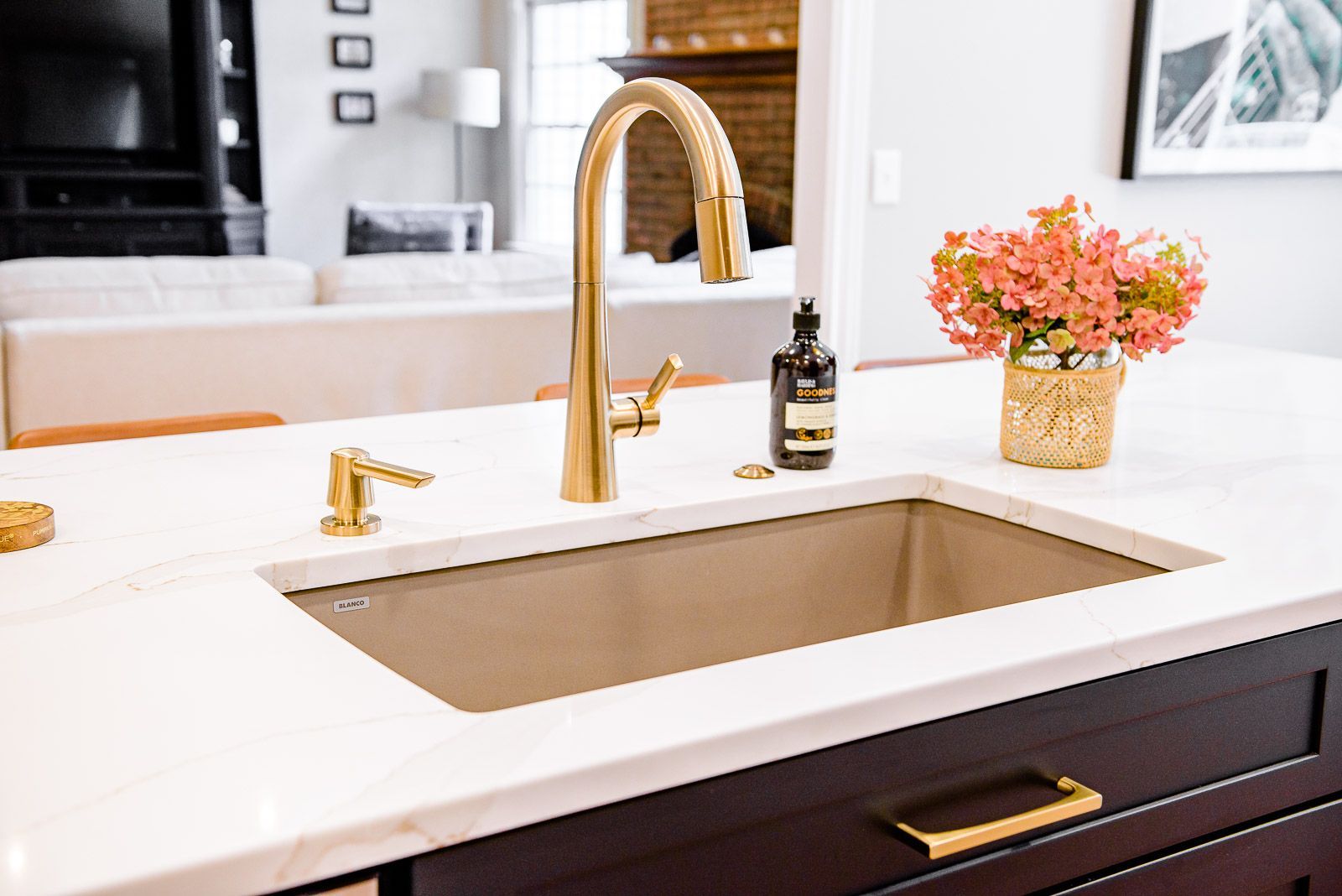 A kitchen sink with a faucet and a vase of flowers on the counter.