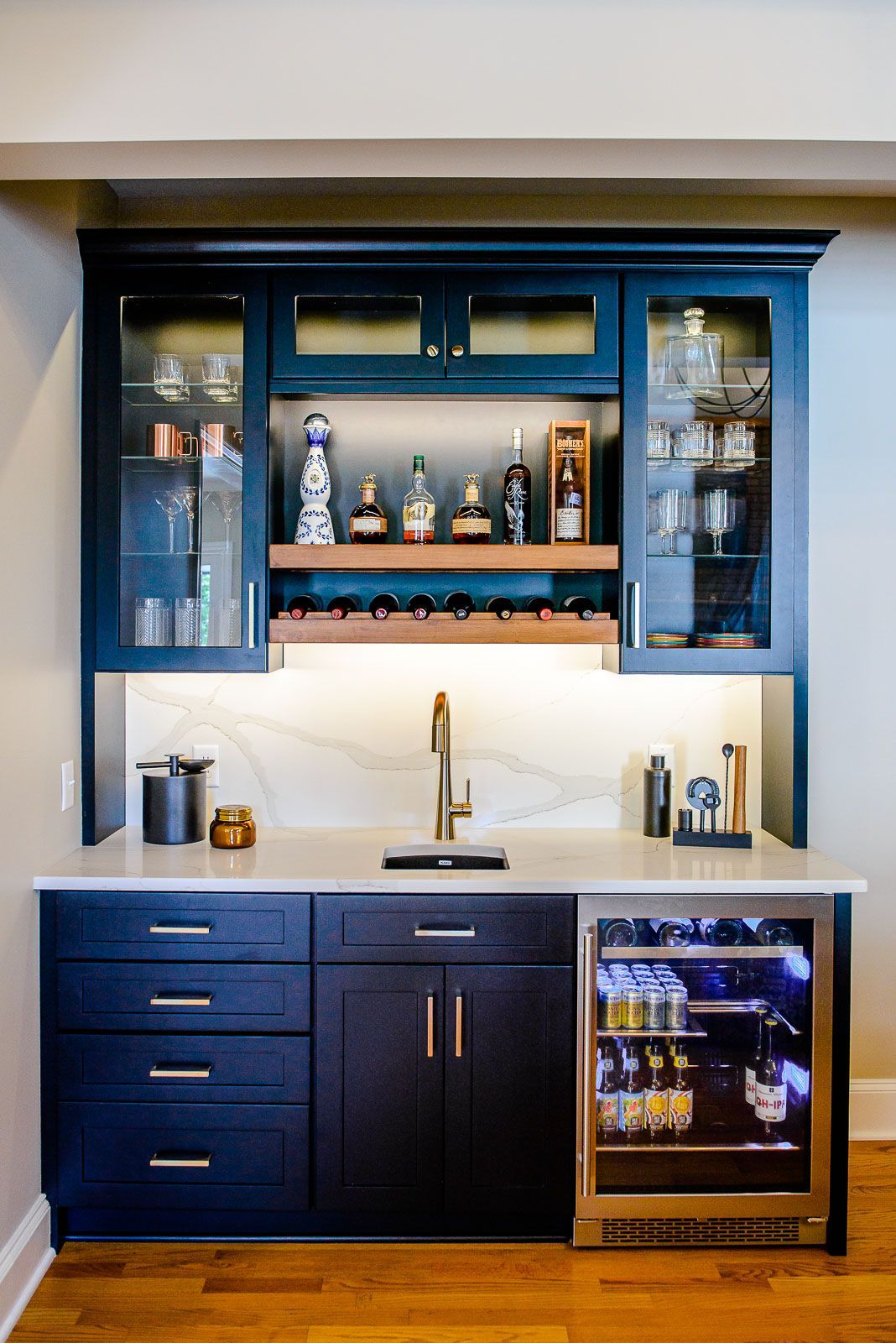 A kitchen with blue cabinets , a sink , a refrigerator and a wine cooler.