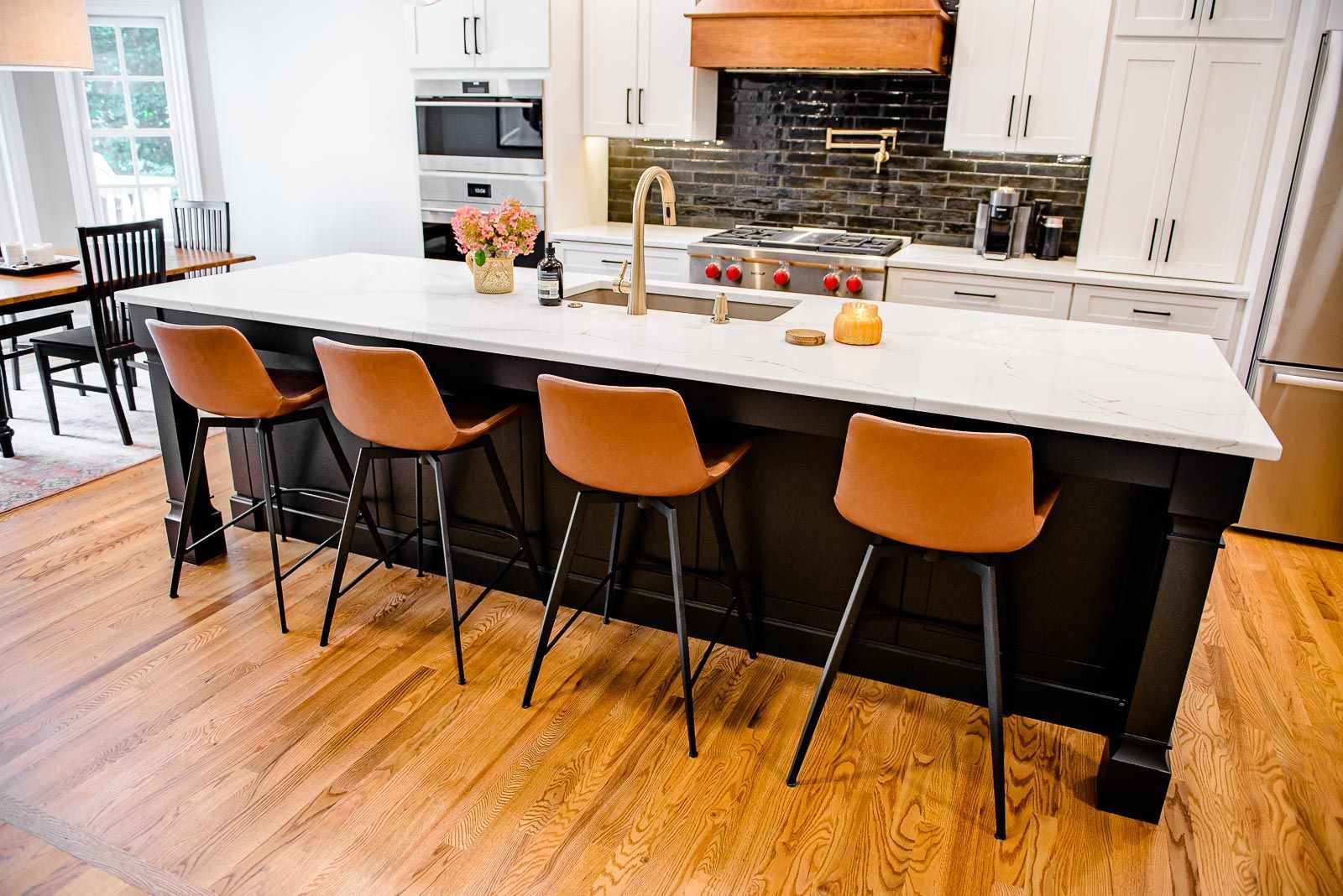 A kitchen with a large island and stools in it.