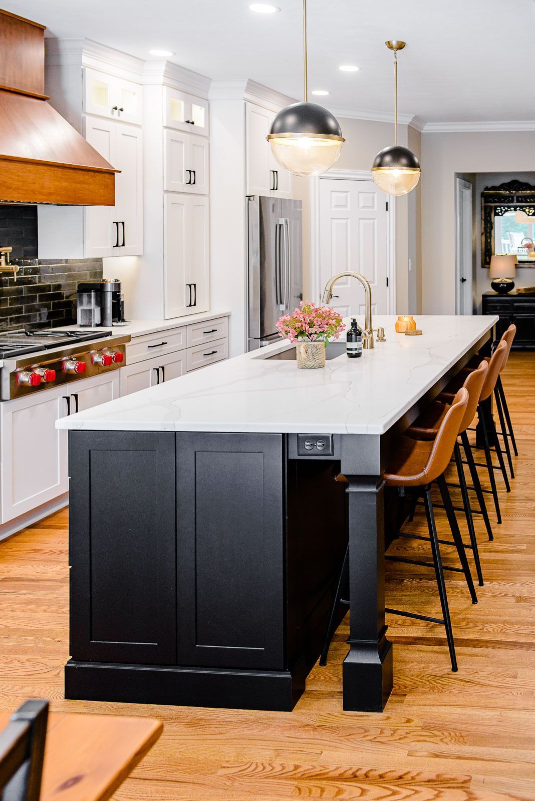 A kitchen with a large island and stools in it.