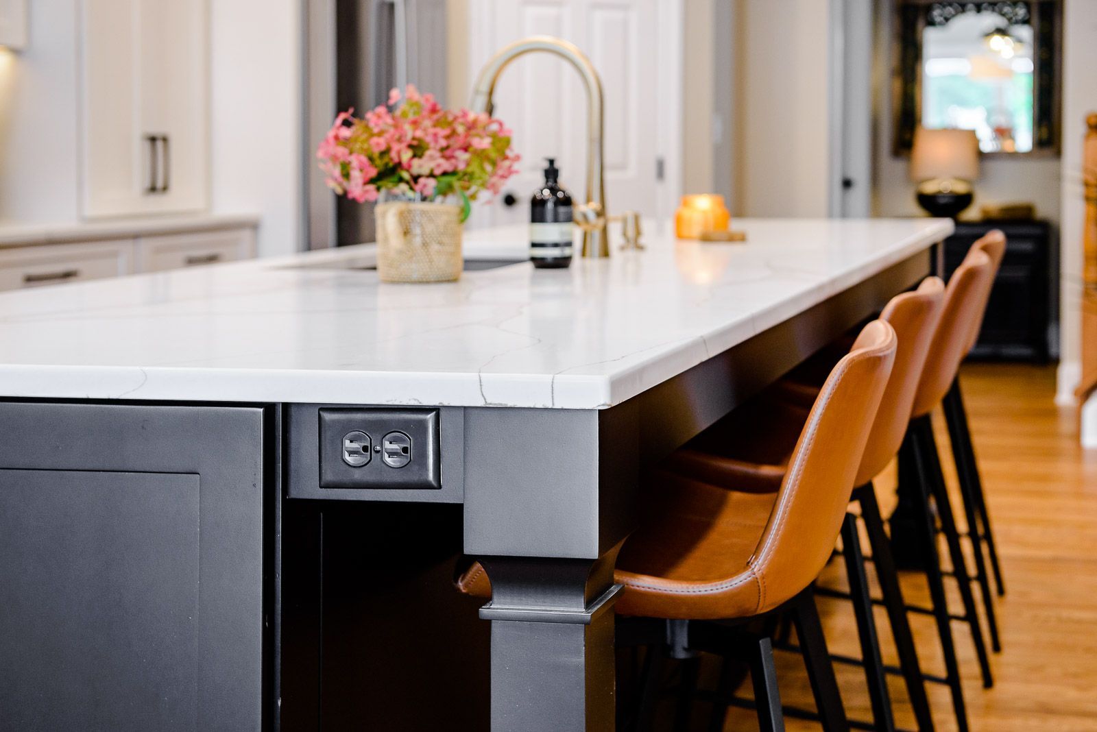A kitchen with a large island and stools and a sink.