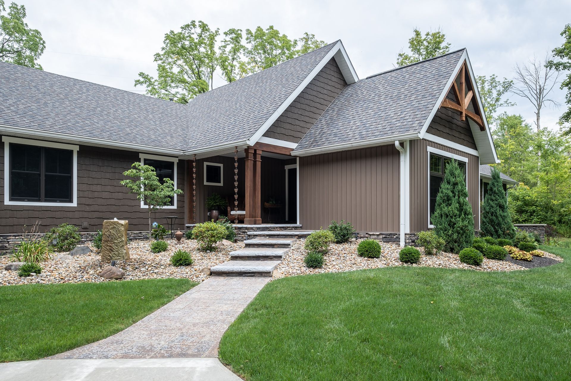 Brown house with gray roof, walkway, steps, and landscaping.