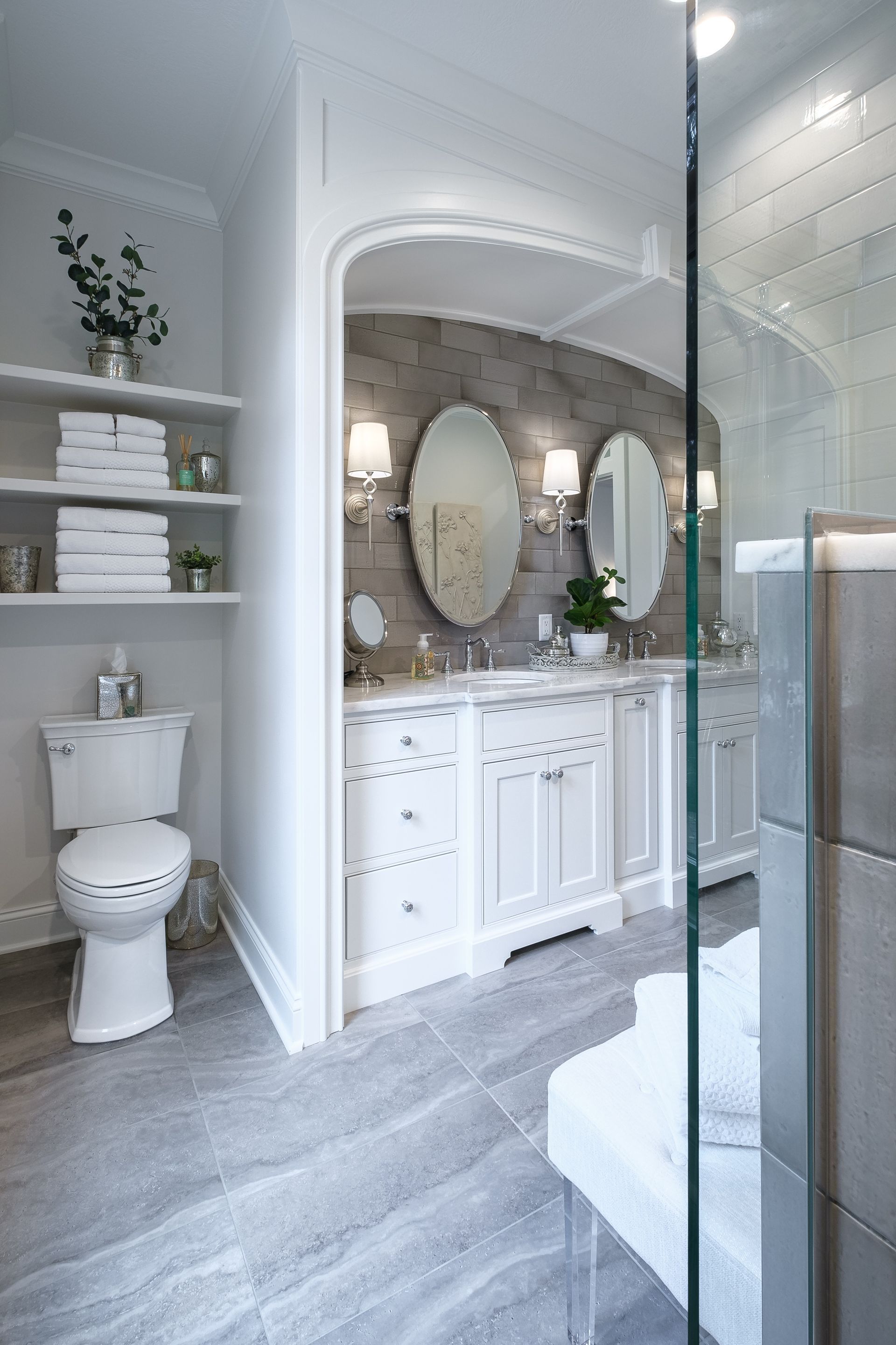 Elegant bathroom with white cabinetry, gray stone tile, dual sinks, and a walk-in shower.