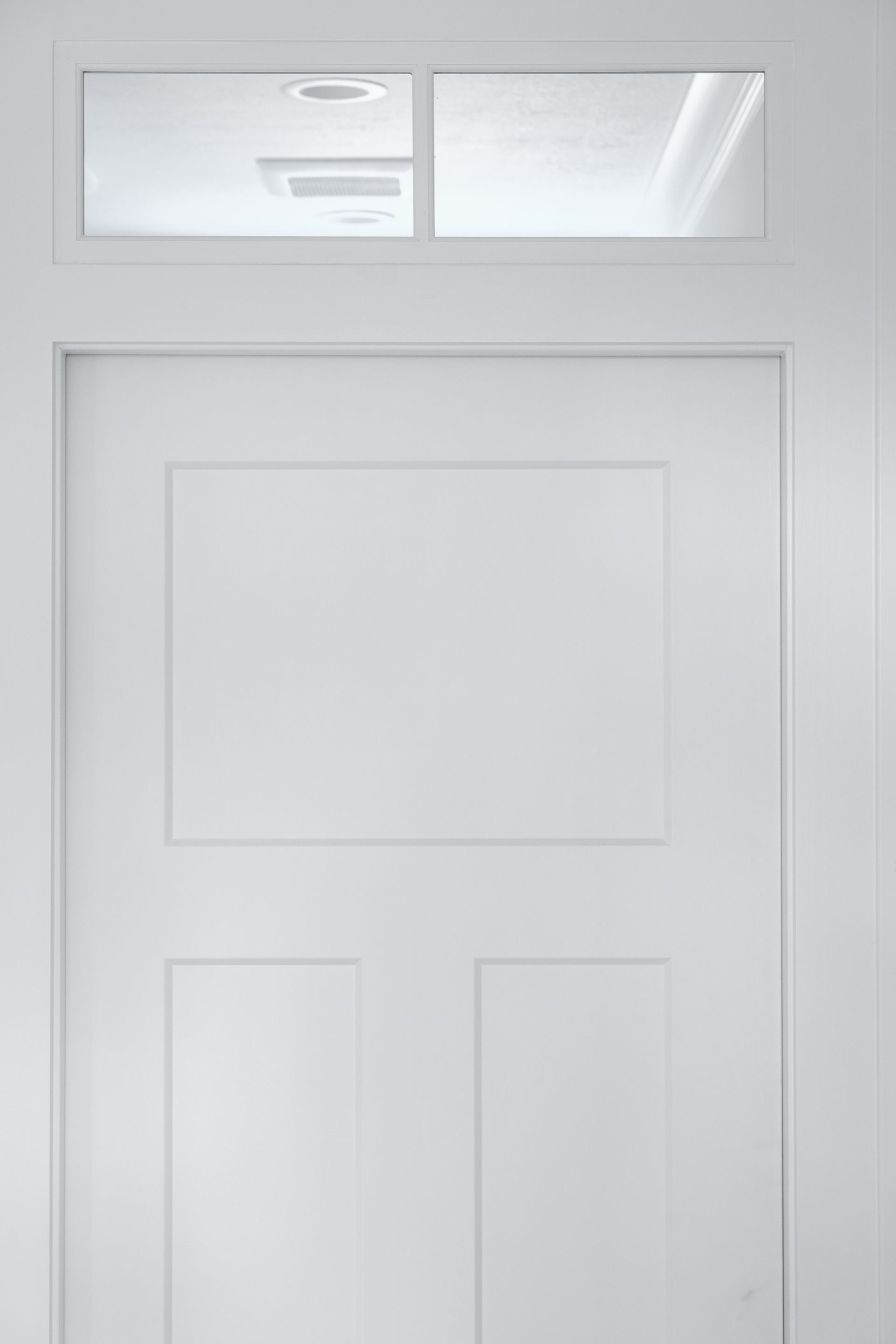 White door with a rectangular top panel and three bottom panels; small window above.