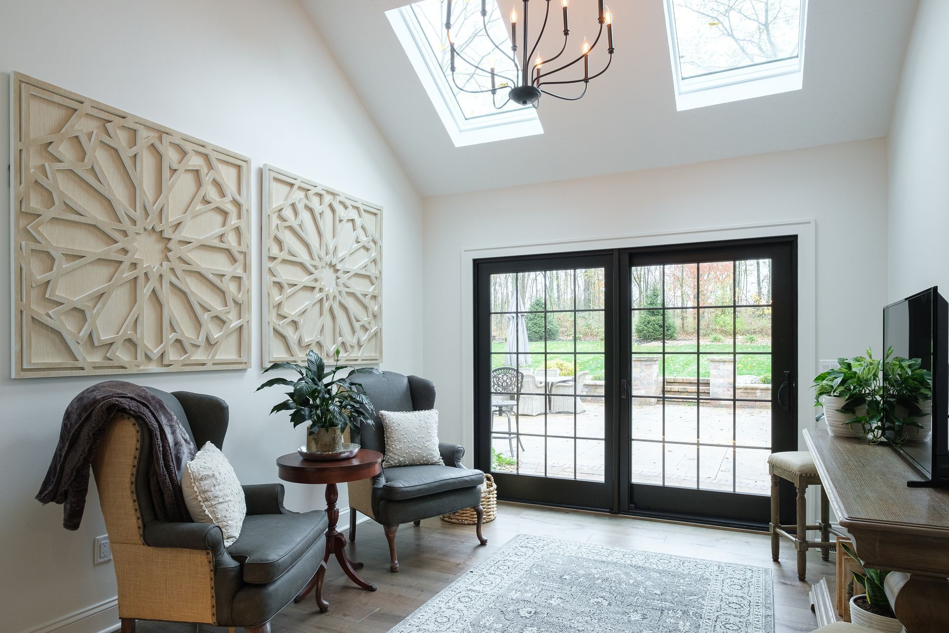 Bright sitting room with two armchairs, decorative wall art, and glass doors opening to a patio.