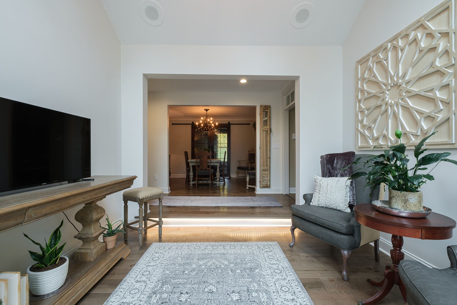 Living room with a TV, a rug, a chair, and an opening to a dining room.