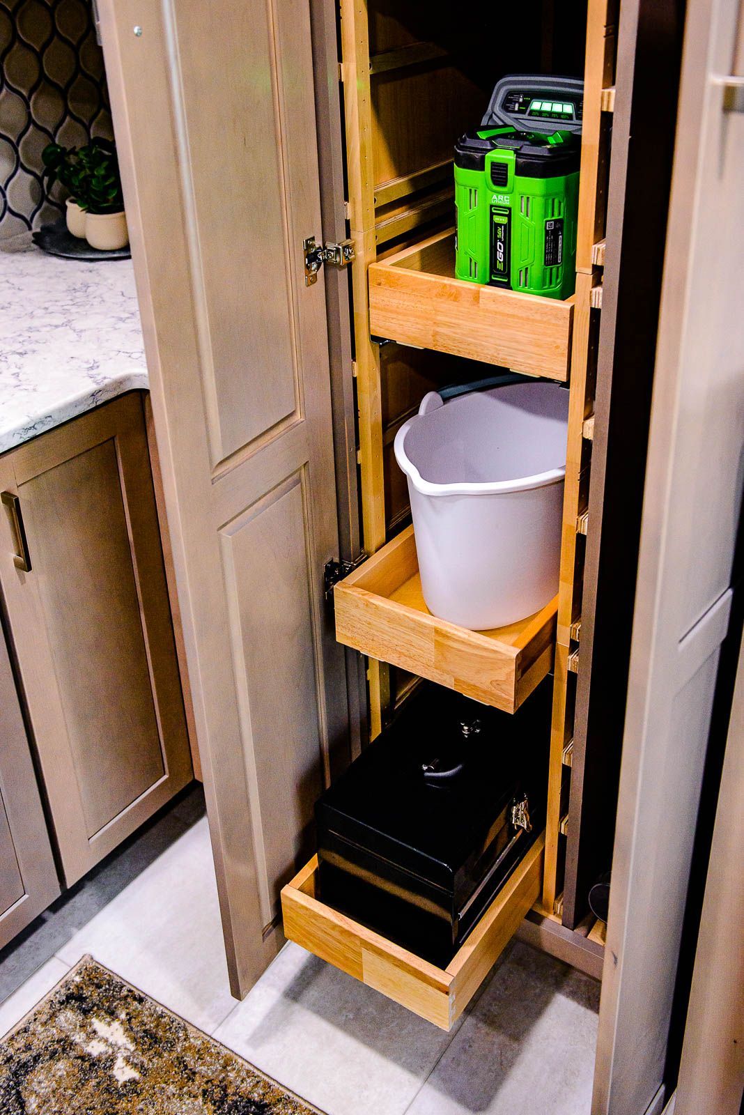 A kitchen cabinet with drawers and a bucket in it.