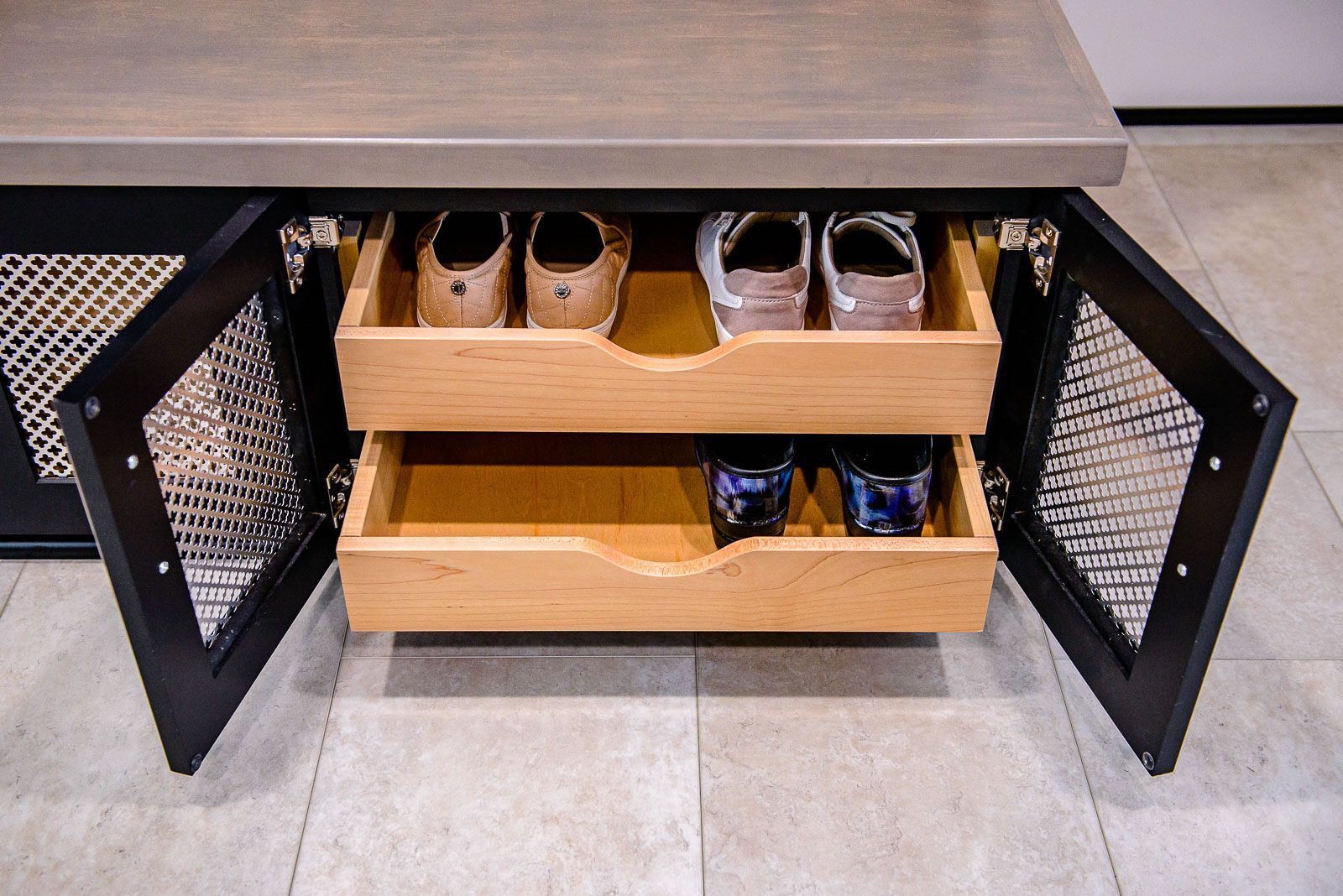 A wooden cabinet with two drawers filled with shoes and glasses.