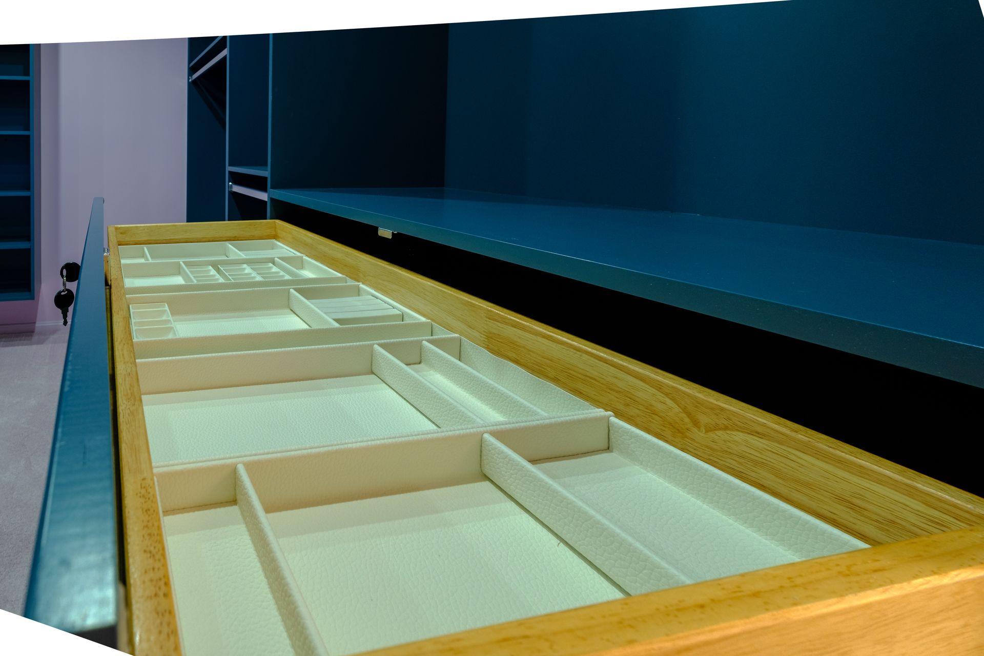 Open wooden drawer with beige compartments, inside a blue cabinet.