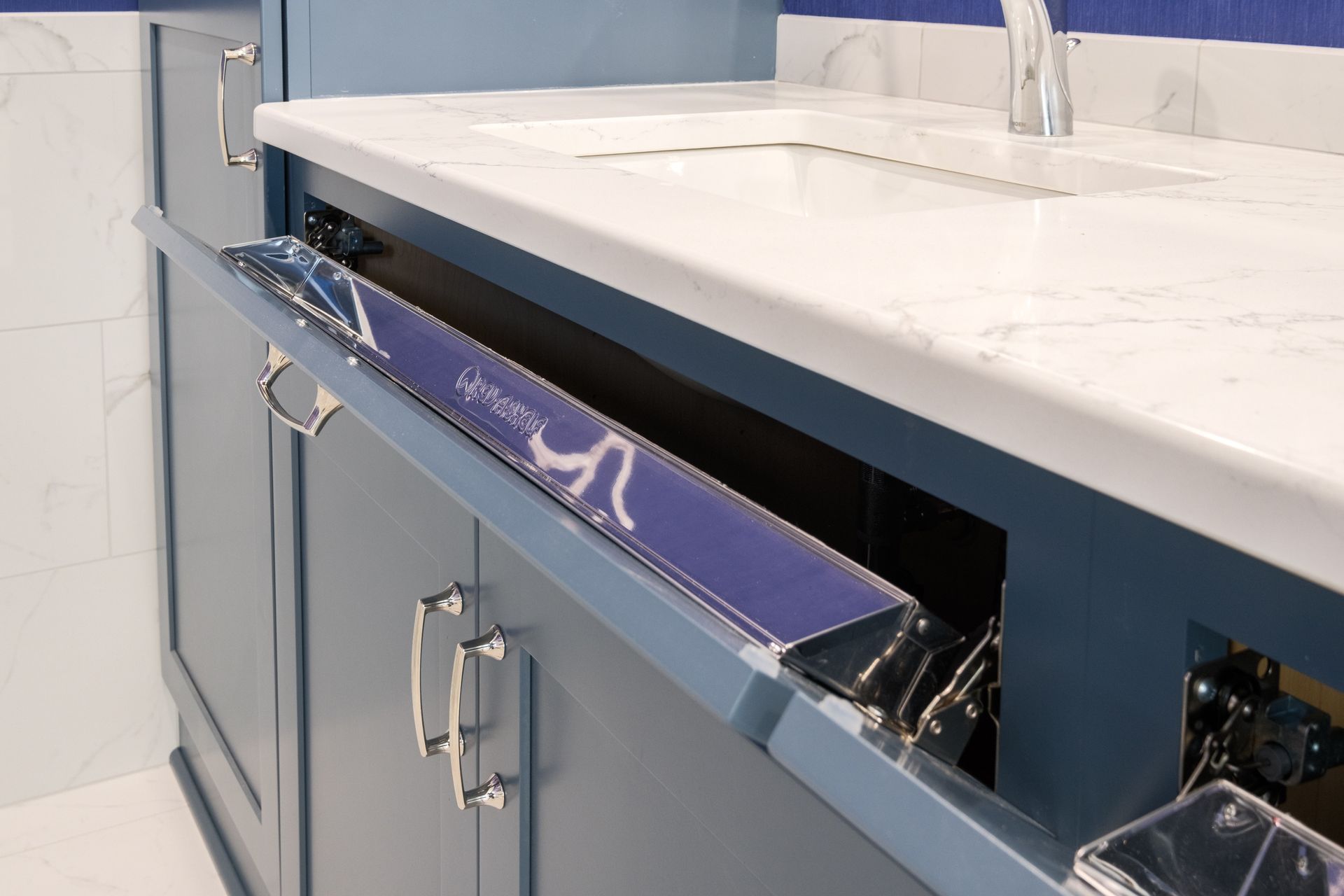 Blue bathroom vanity with a pull-out drawer under the sink, showcasing plumbing.