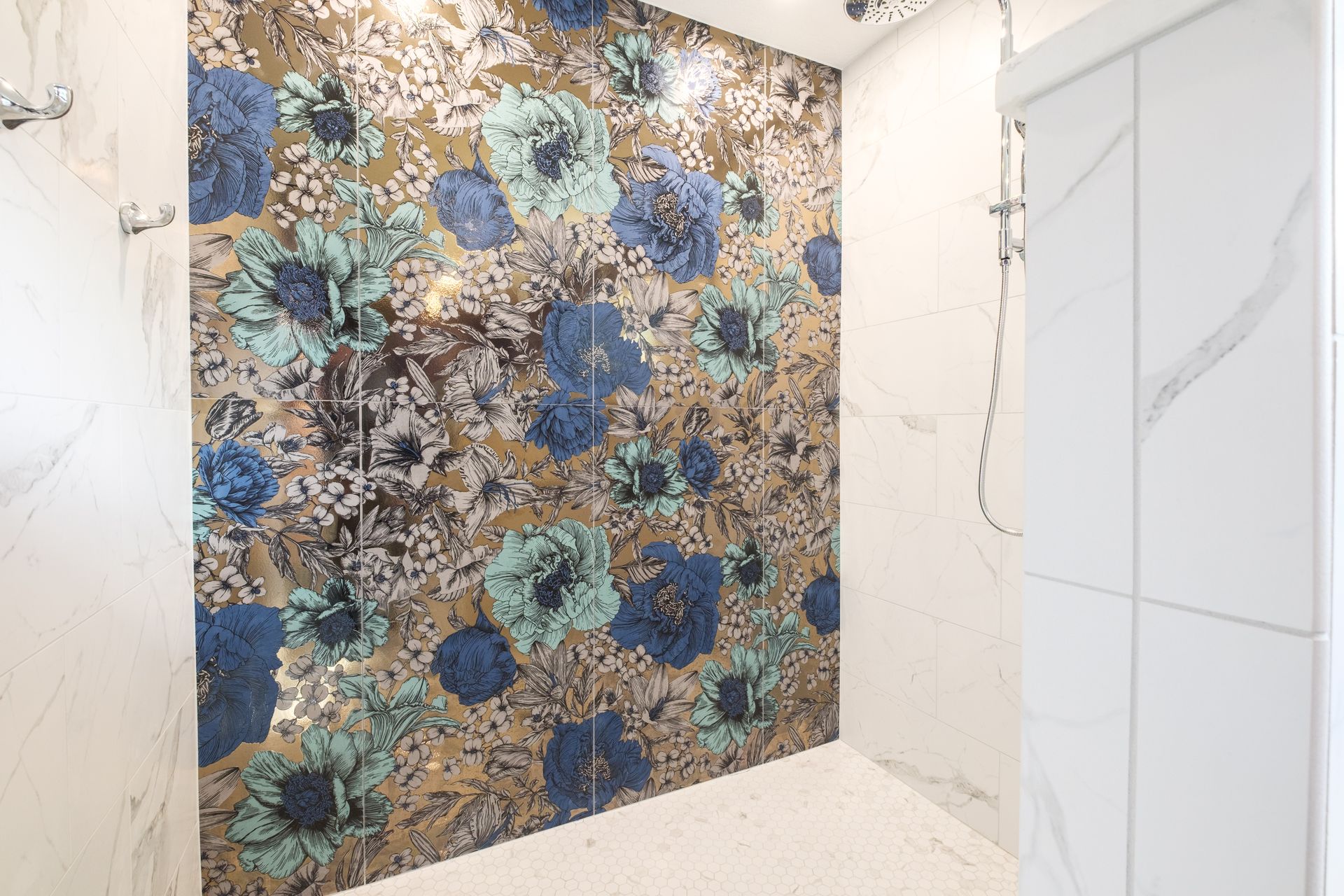 Shower with a floral accent wall featuring blue and teal flowers, surrounded by white marble tiles.