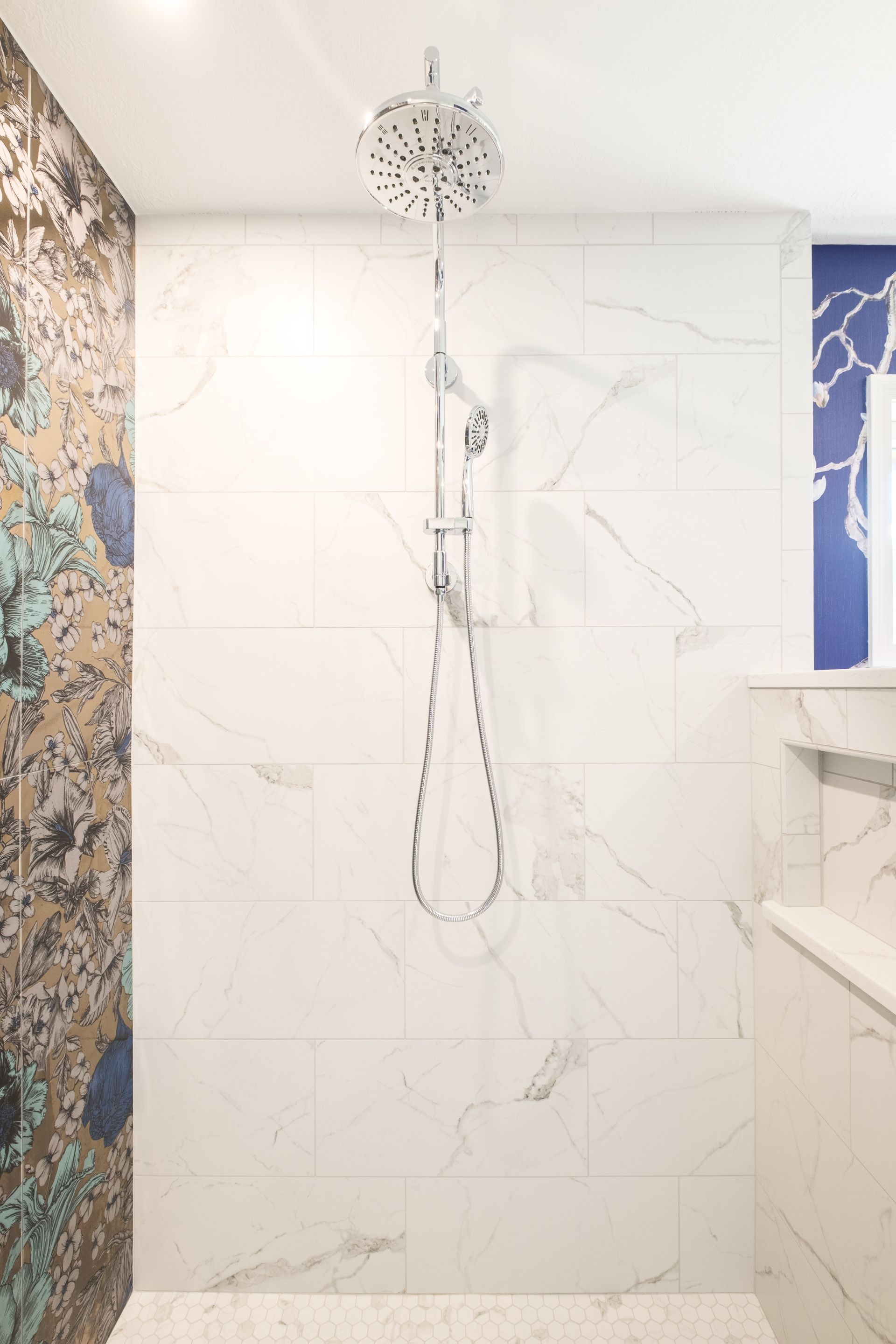 Shower with marble-look white tiles, a large rain showerhead, and a mosaic accent wall.