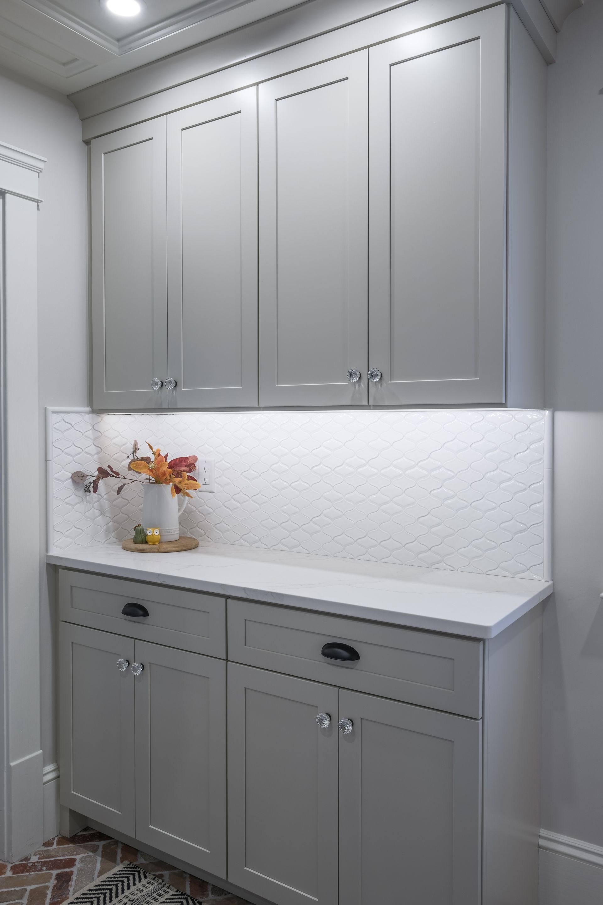 A laundry room with gray cabinets and white counter tops.