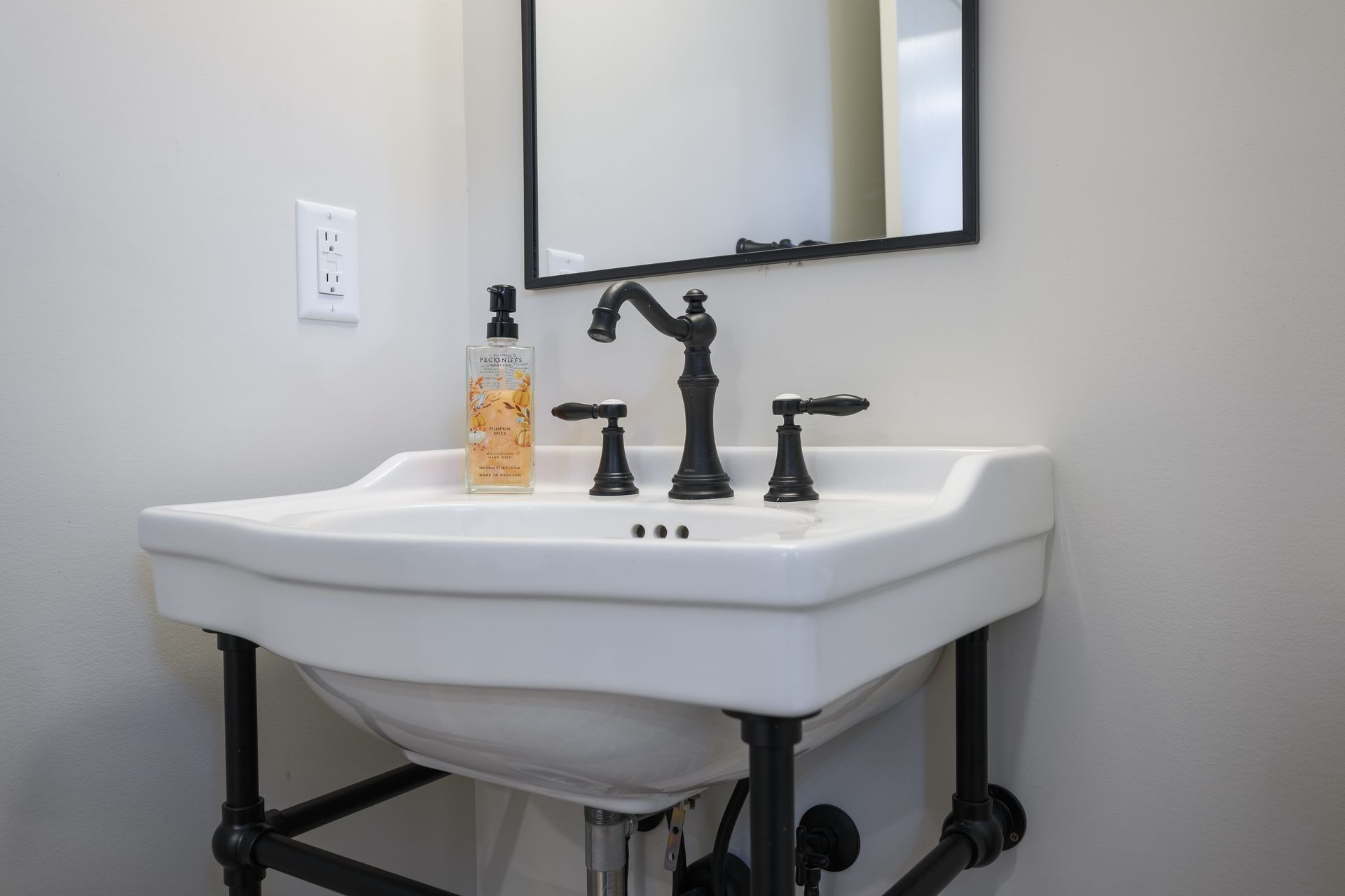 A bathroom sink with a mirror and a soap dispenser on it.