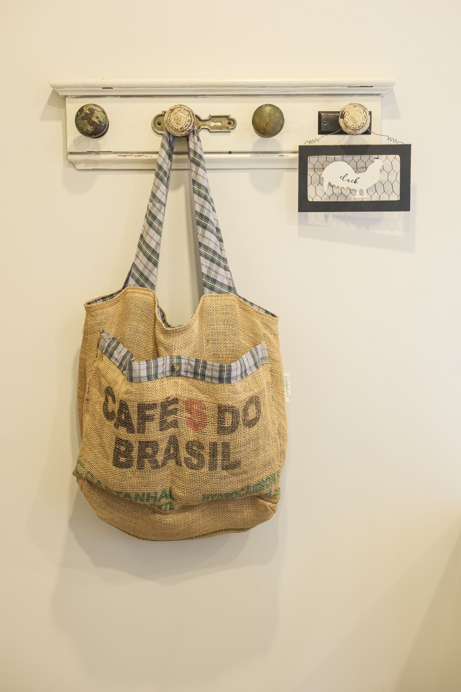 A straw bag is hanging on a hook on a wall.