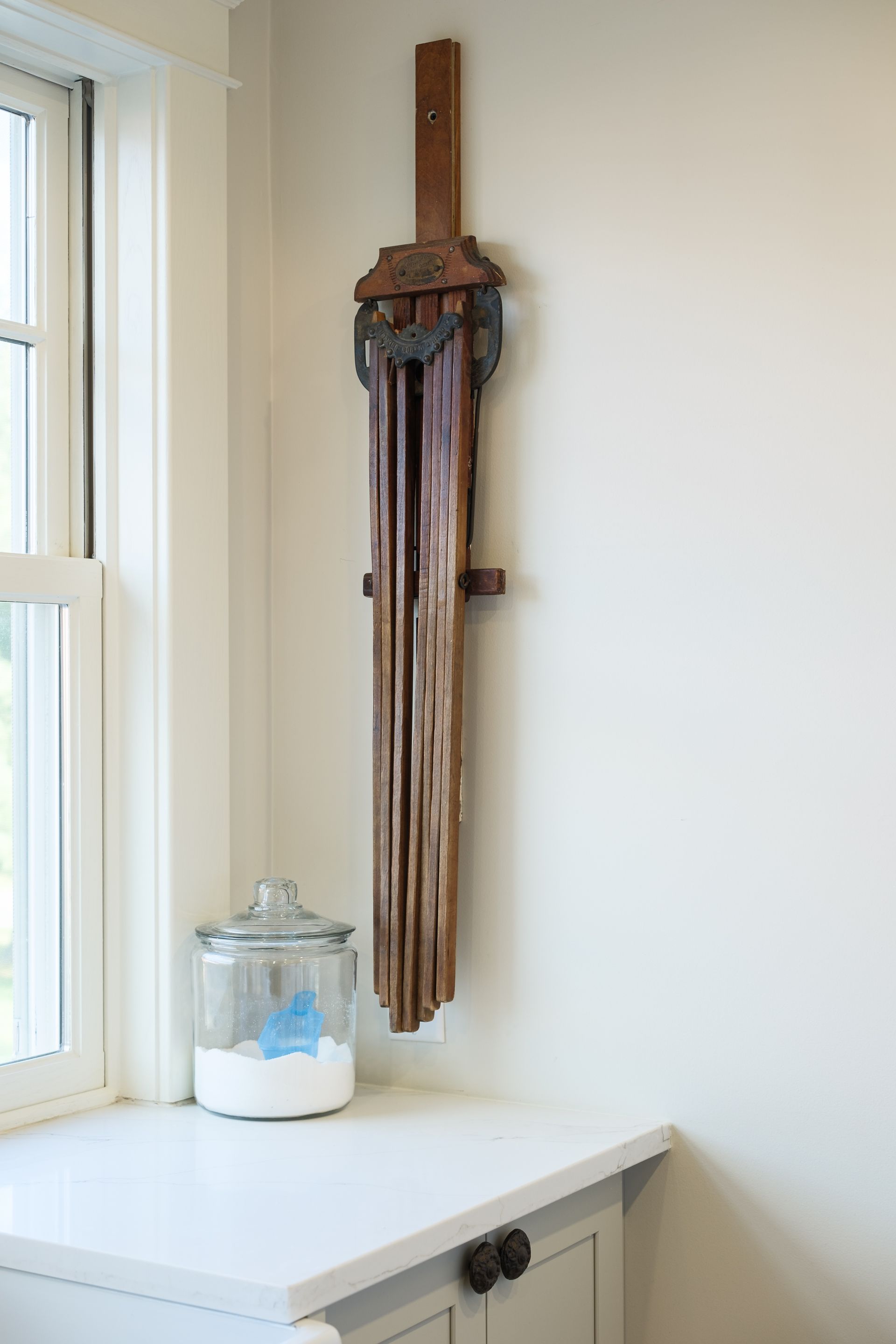 A jar of laundry powder sits on a counter next to a window