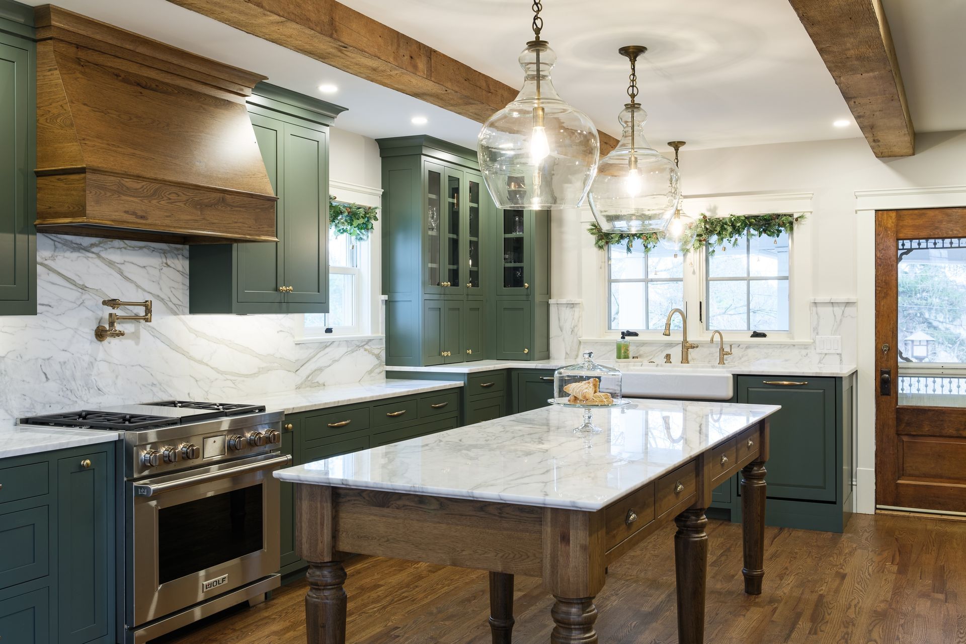 A kitchen with green cabinets and a large table in the middle.
