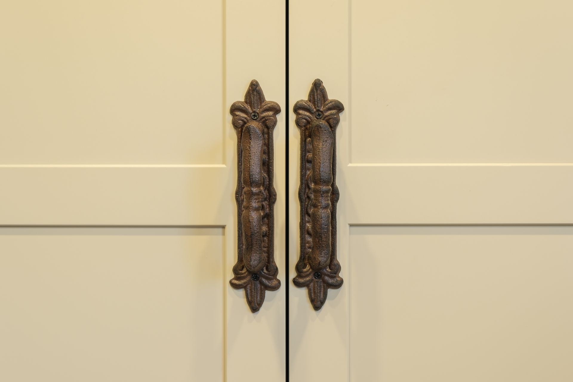 A close up of a pair of door handles on a white cabinet.