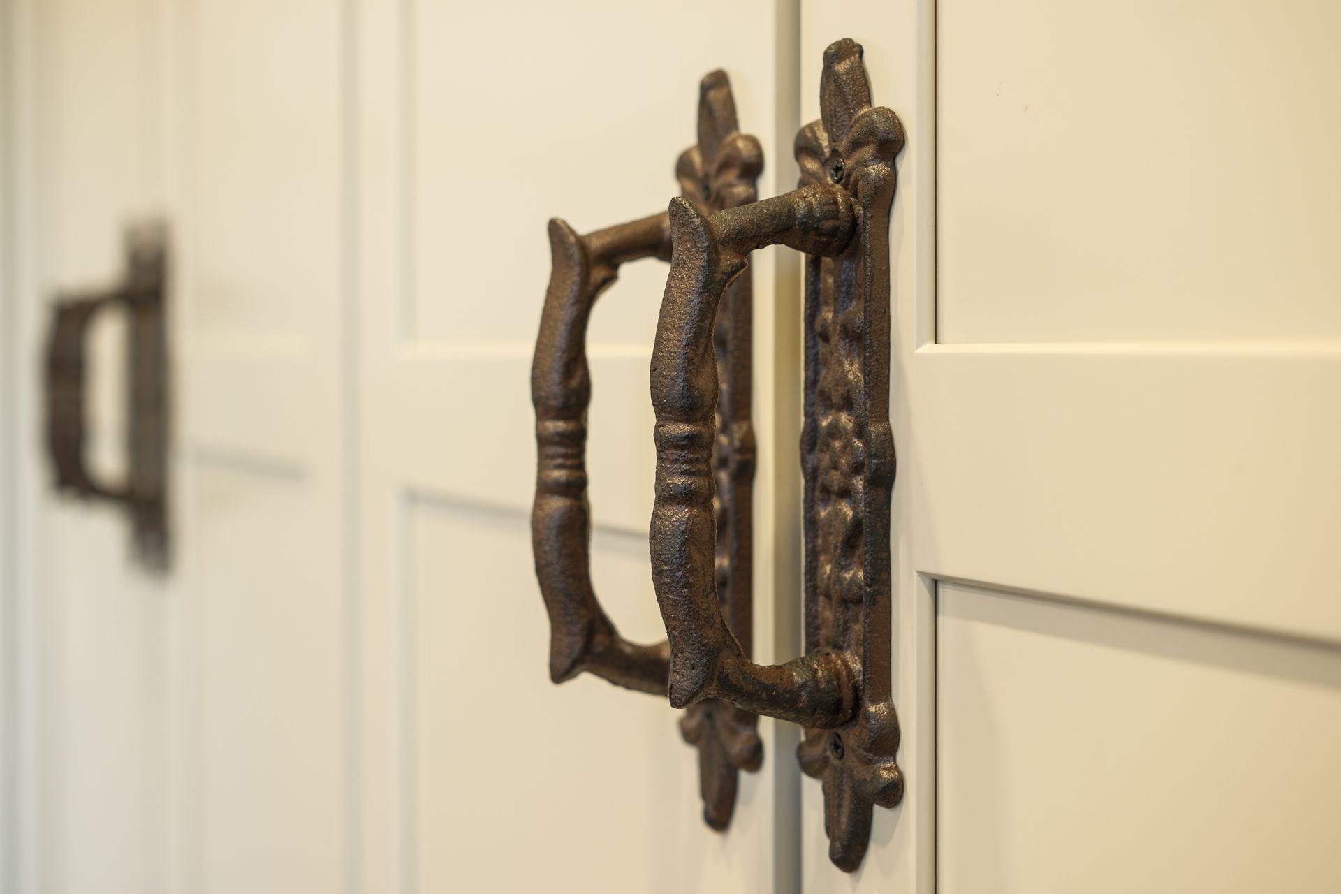 A close up of a door handle on a white cabinet