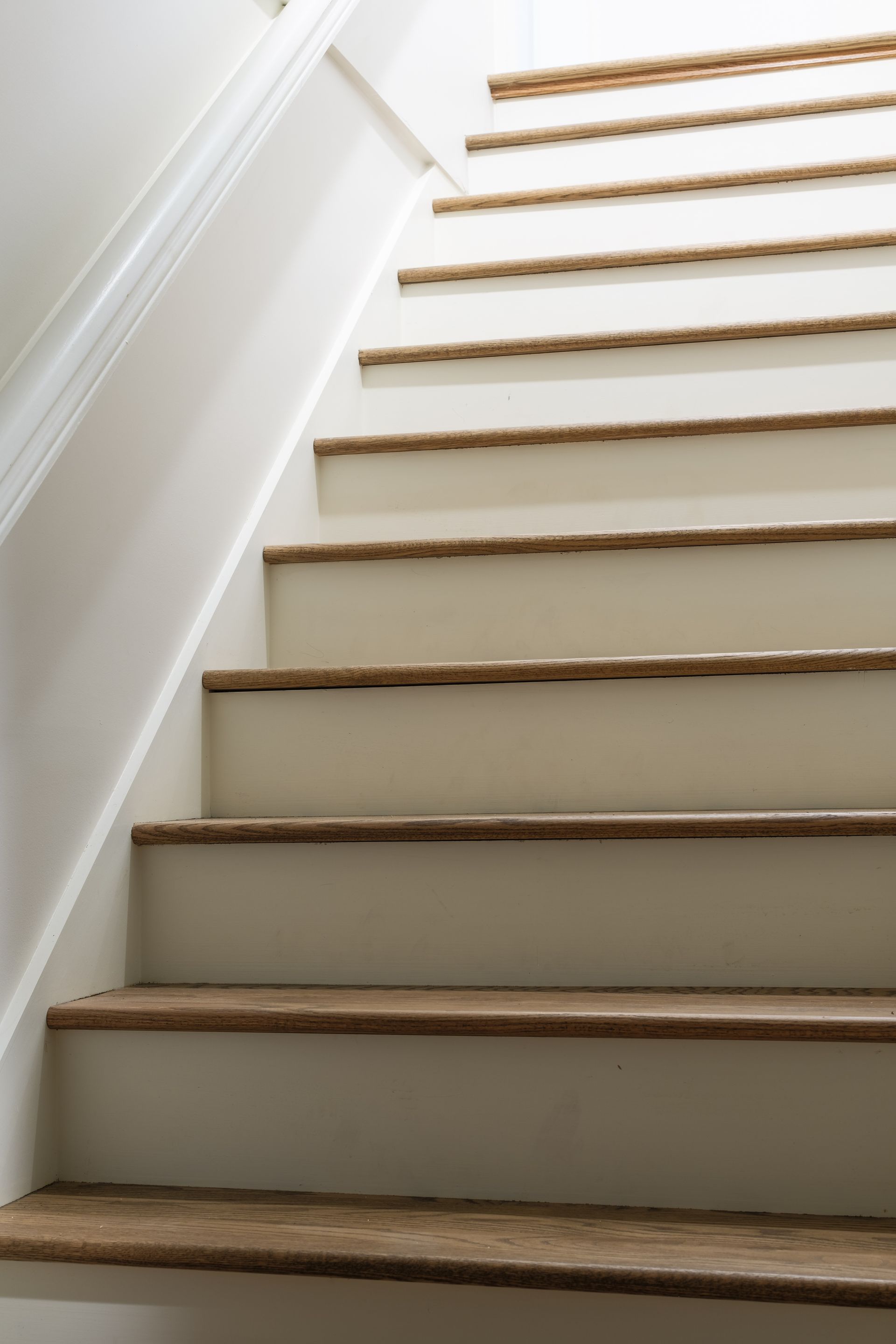 A close up of a set of stairs with wooden steps and a white railing.