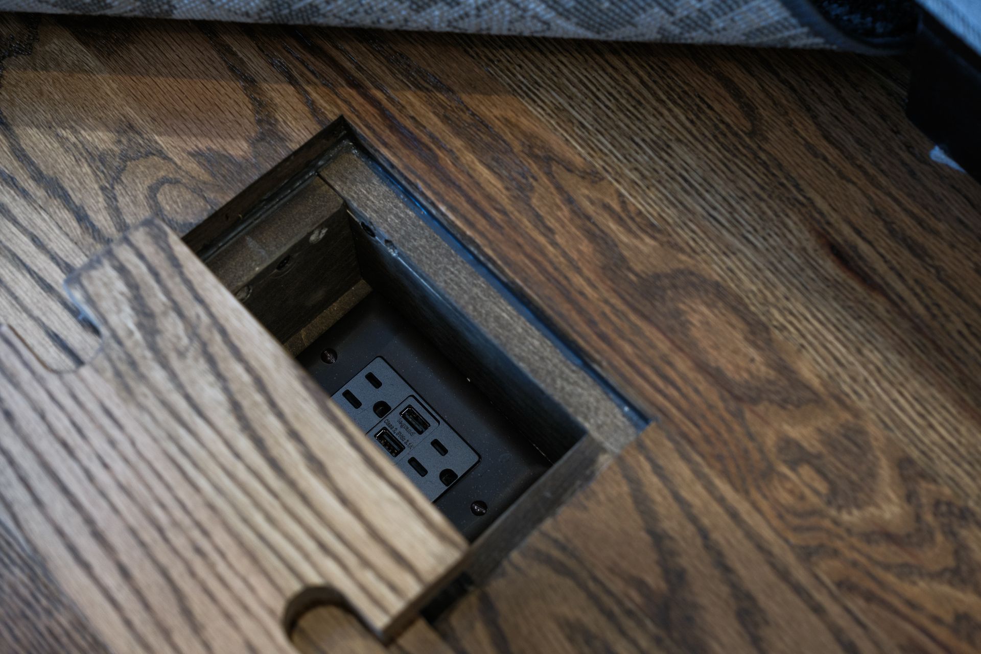 A wooden table with a hidden electrical outlet underneath it.