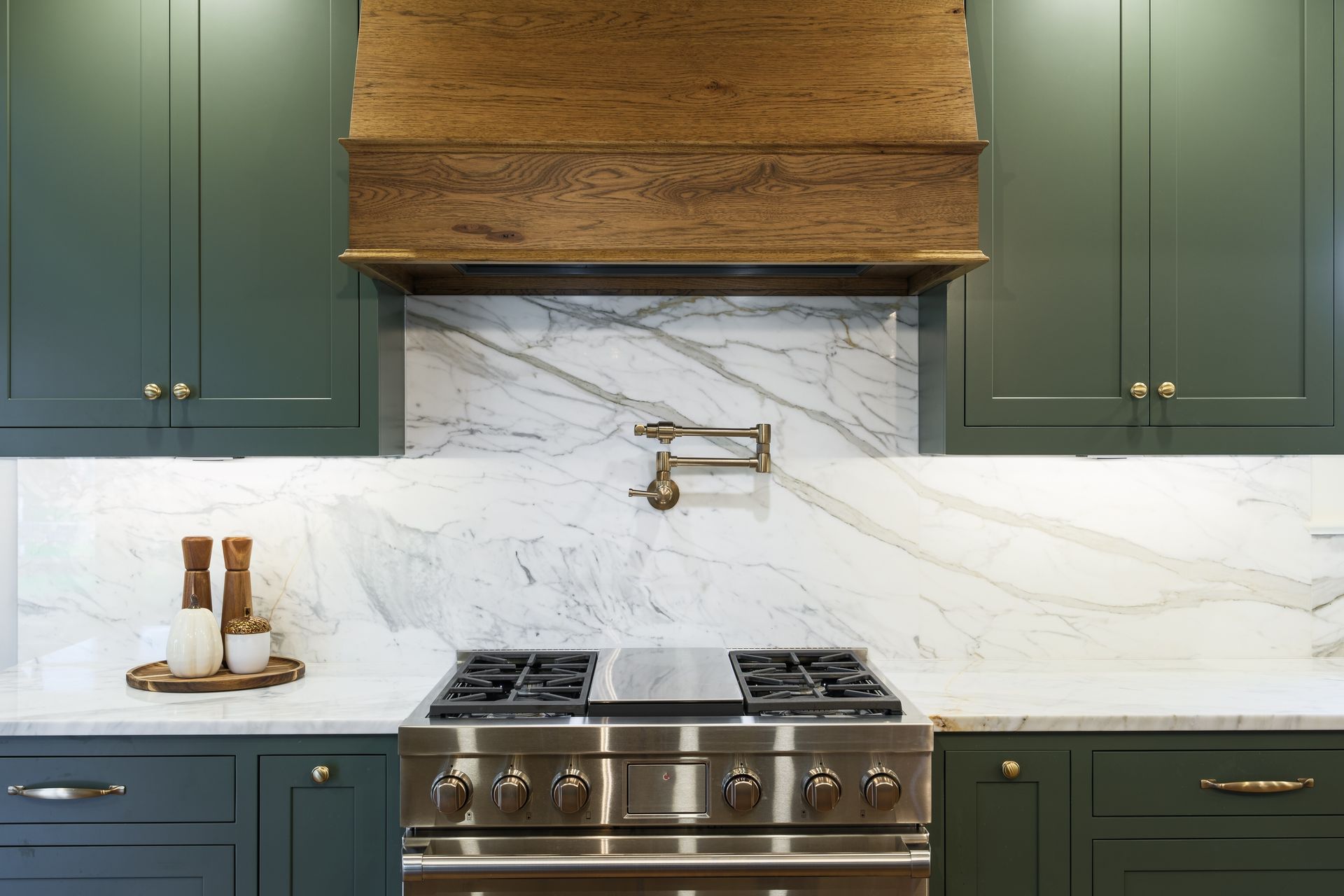 A kitchen with green cabinets and a stainless steel stove top oven.