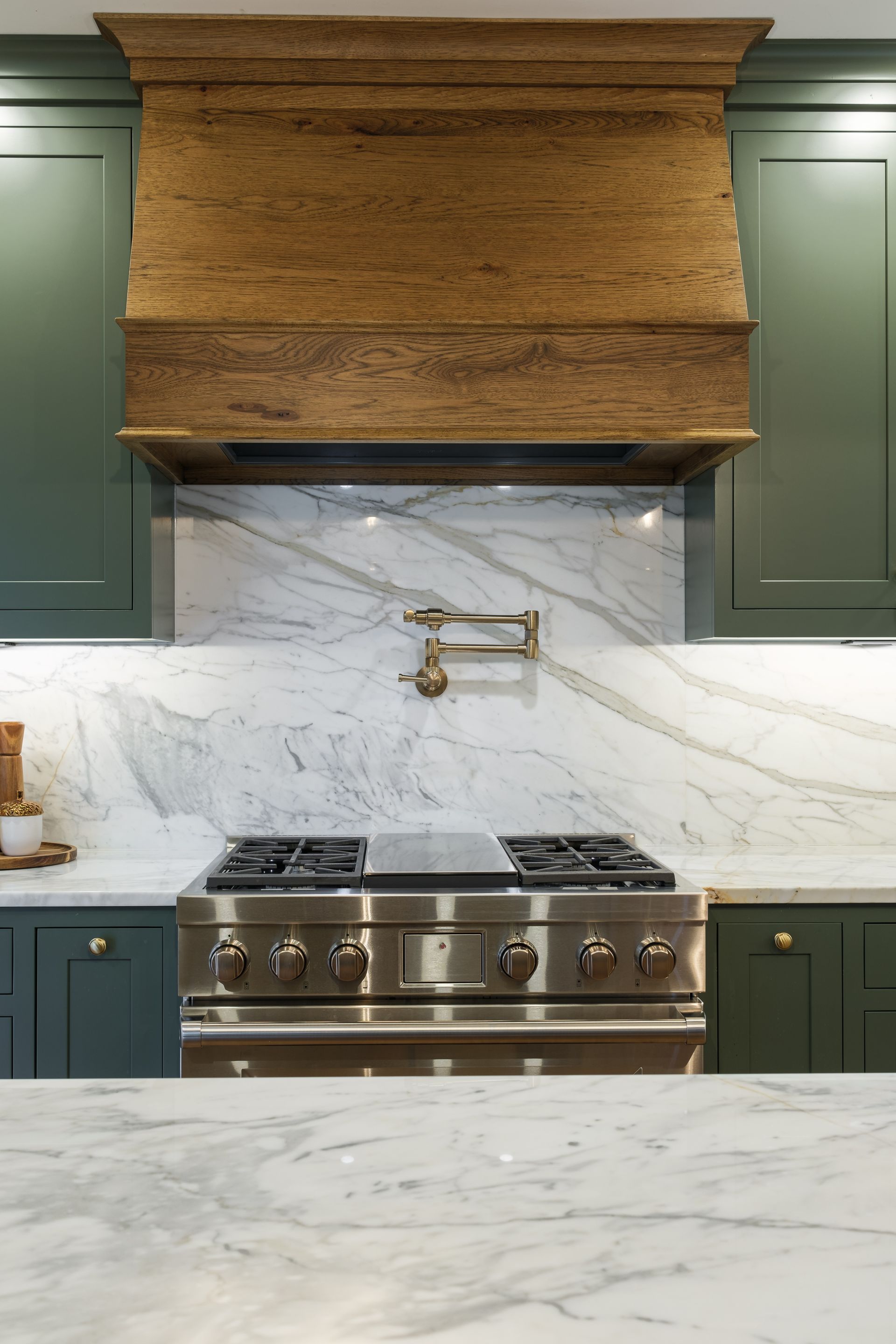 A kitchen with a stove and a hood above it.