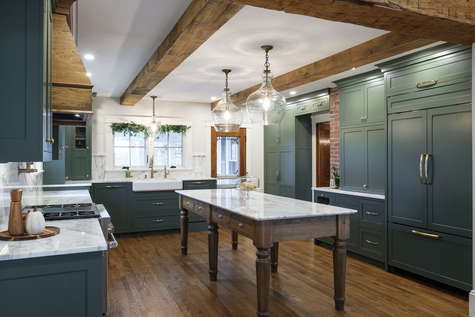 A kitchen with green cabinets and a large table in the middle.