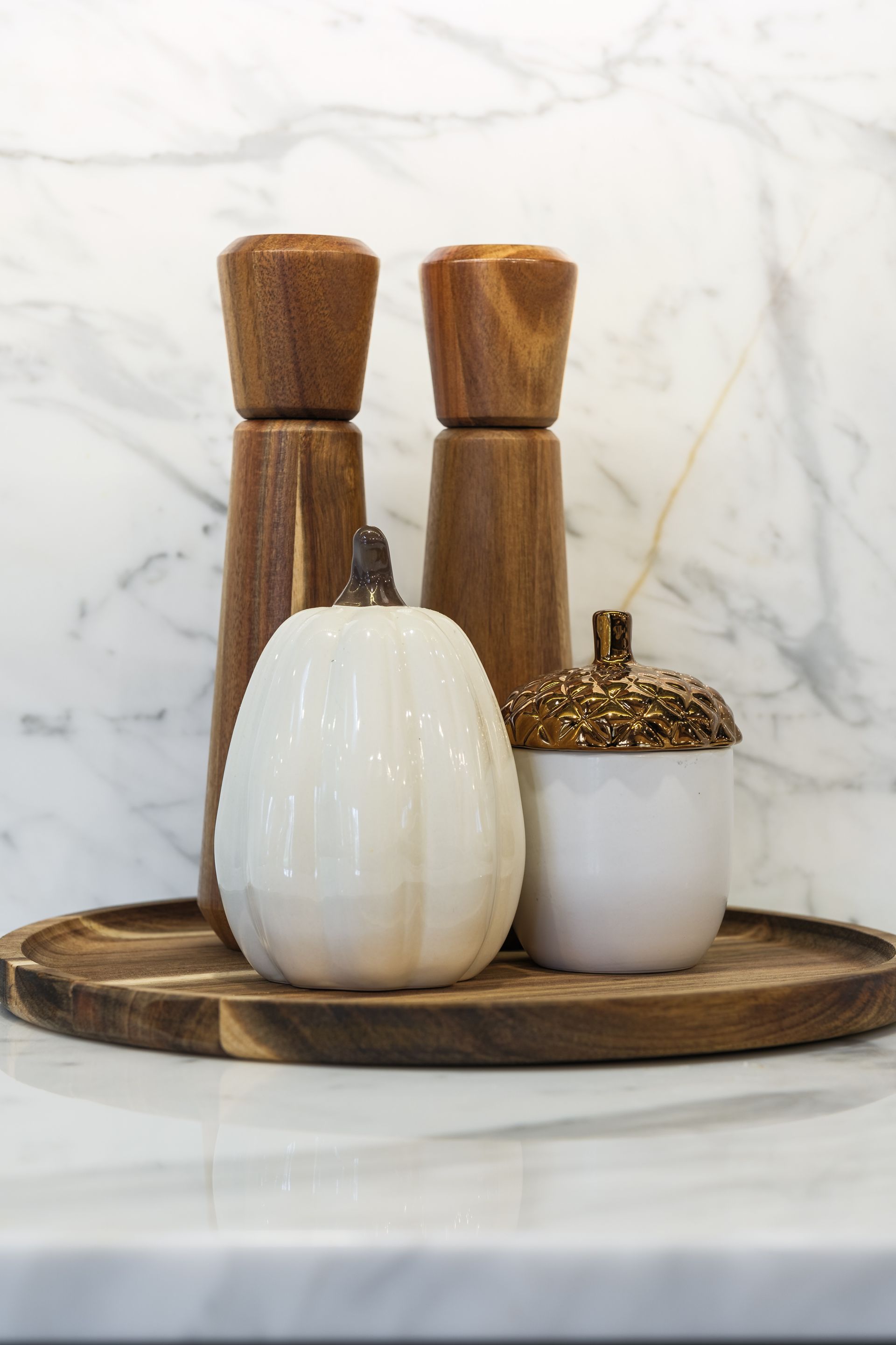 A wooden tray with salt and pepper shakers , acorns and pumpkins on it.
