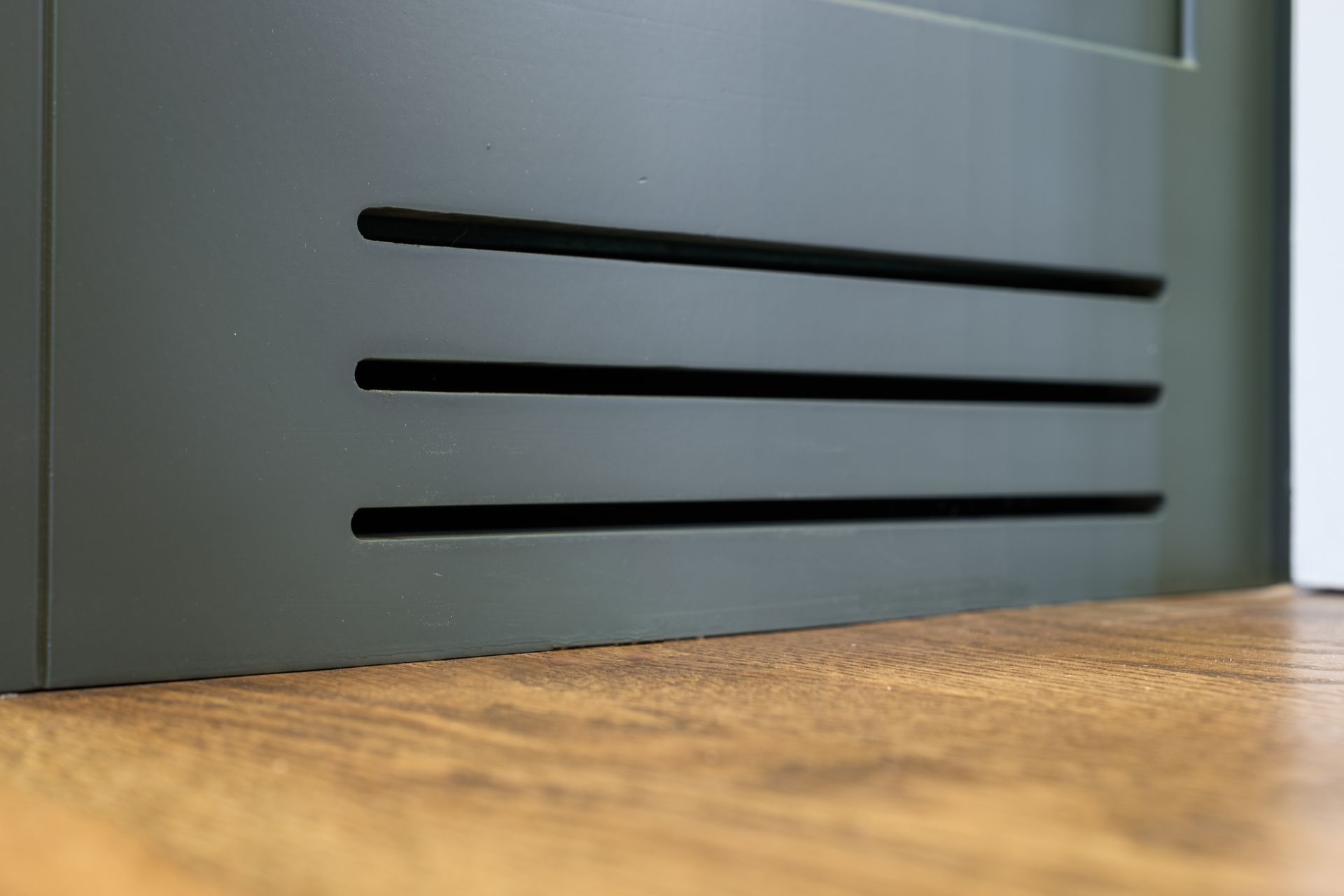 A close up of a metal door with three lines on it on a wooden floor.