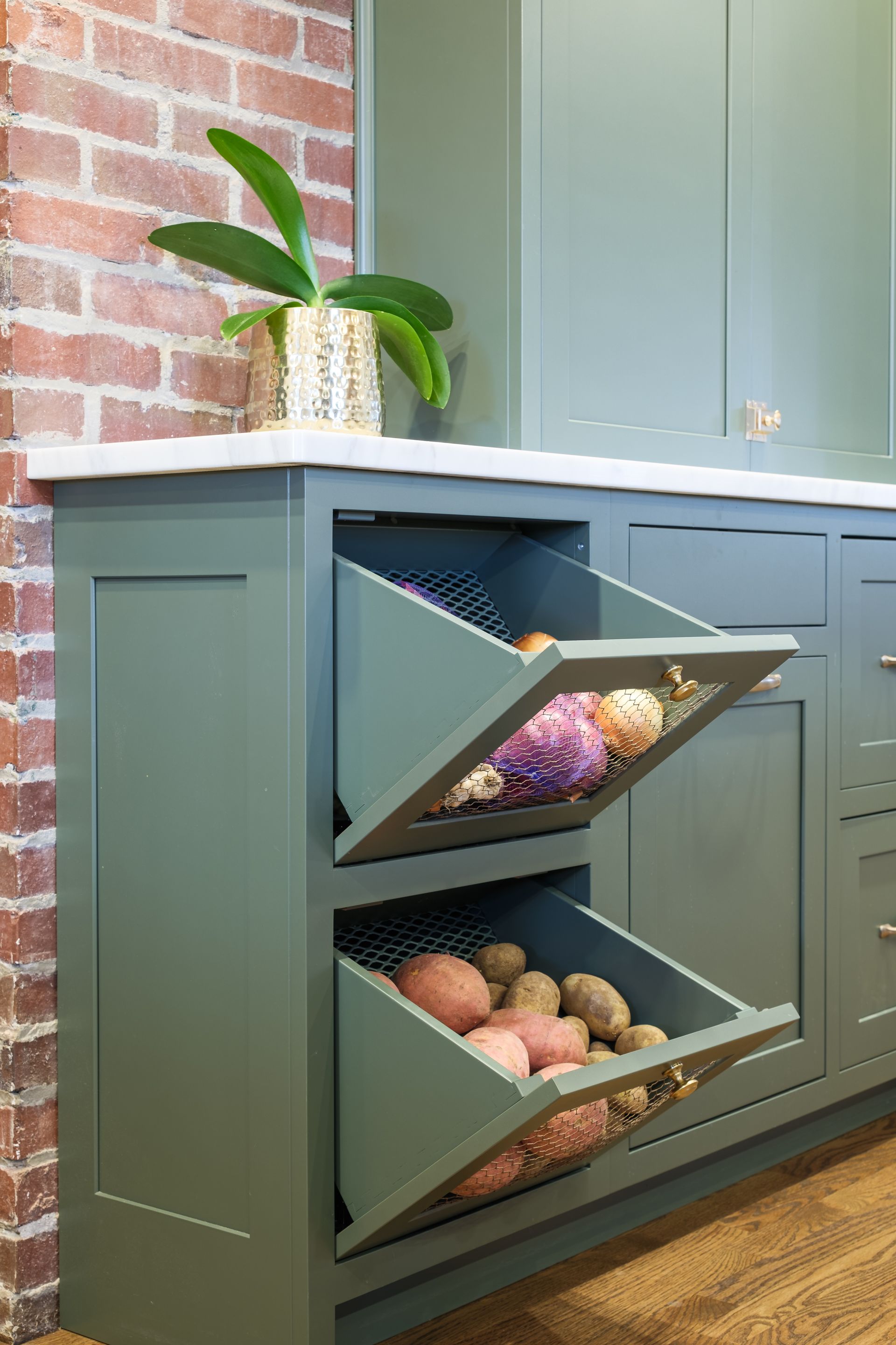 A kitchen counter with two baskets filled with potatoes and vegetables.