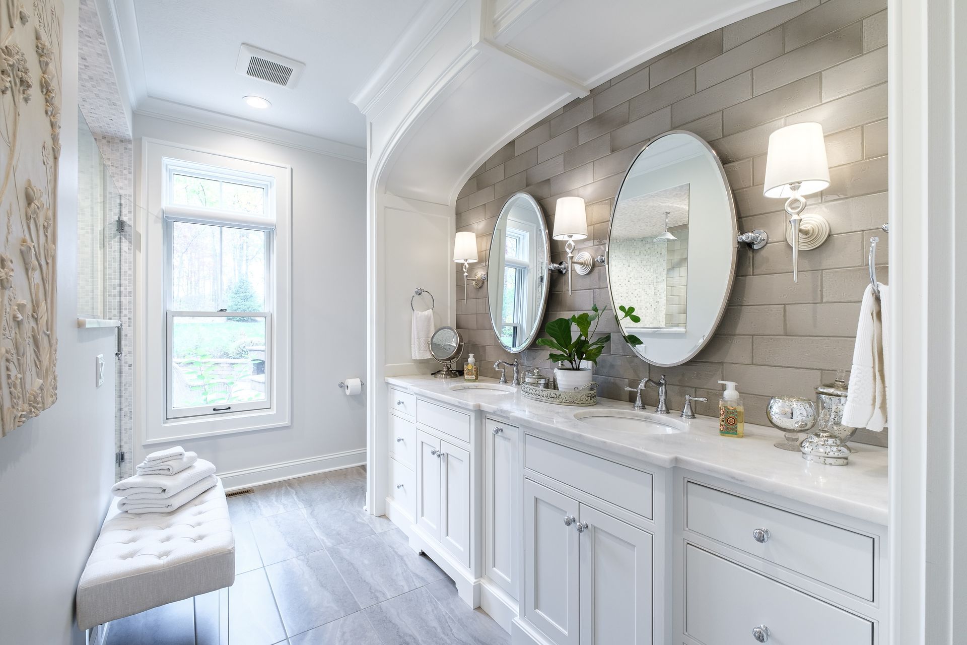 A bathroom with two sinks , two mirrors and a bench.