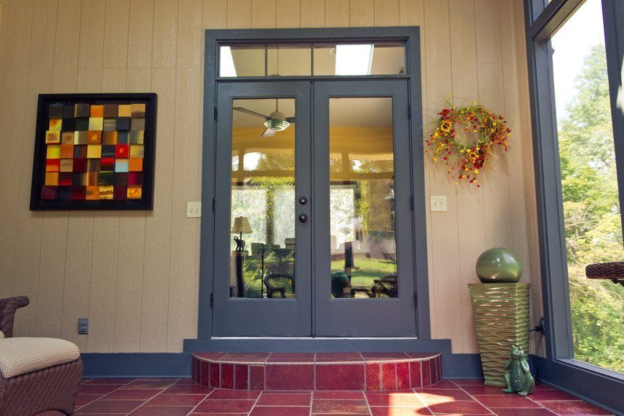 A screened in porch with a chair and a wreath on the wall