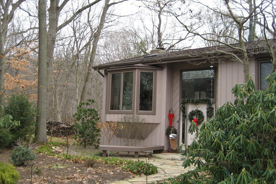 A small house in the middle of a forest with a wreath on the door