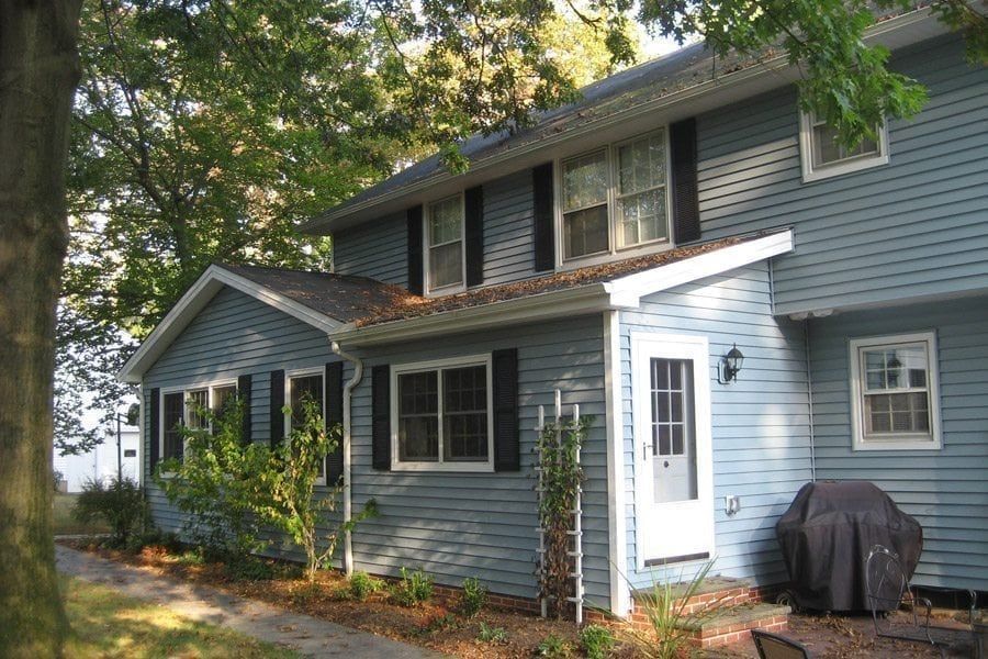 A blue house with black shutters and a grill