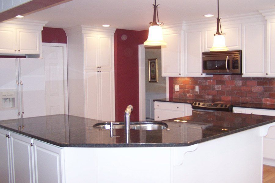 A kitchen with white cabinets and black counter tops