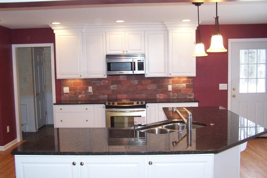 A kitchen with white cabinets and black counter tops