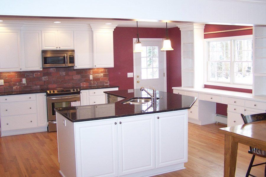 A kitchen with white cabinets and black counter tops