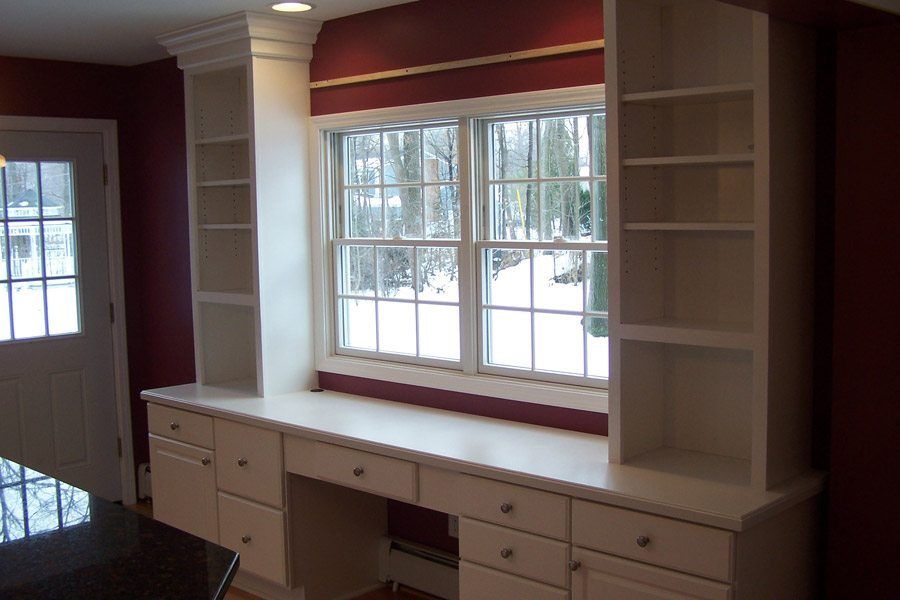 A room with a desk and shelves in front of a window