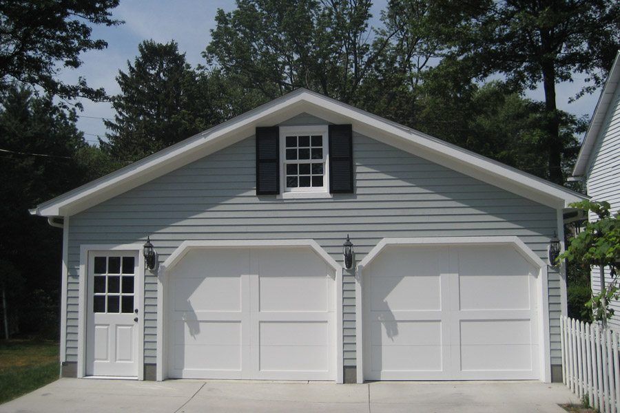 A white garage with black shutters and a window