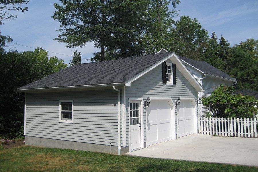 A white house with a garage and a white picket fence